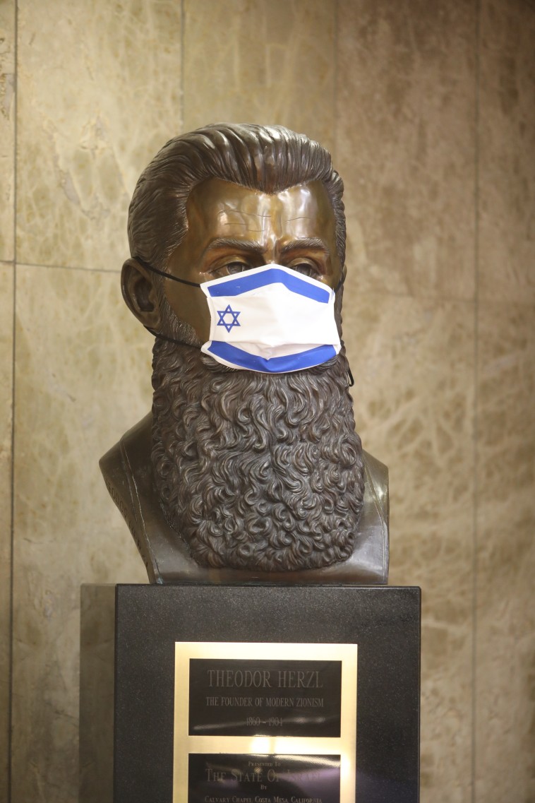 המסכה על פניו של חוזה מדינת היהודים, בנימין זאב הרצל, מזכירה לנו שהנגיף עוד כאן
