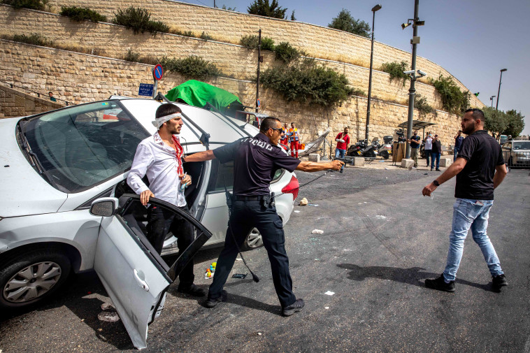 ימים מתוחים: השוטר אלי בן קיקי מגן על קורבן ניסיון לינץ' סמוך לשער האריות בירושלים (צילום: אוליבייה פיטוסי, פלאש 90)