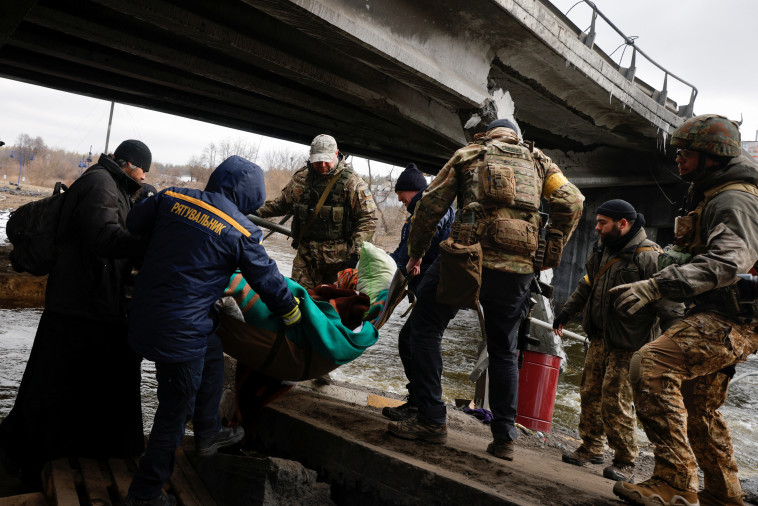 אנשי ביטחון אוקראינים מסייעים לאנשים להימלט מהאזורים שהותקפו על ידי רוסיה (צילום: REUTERS/Thomas Peter)