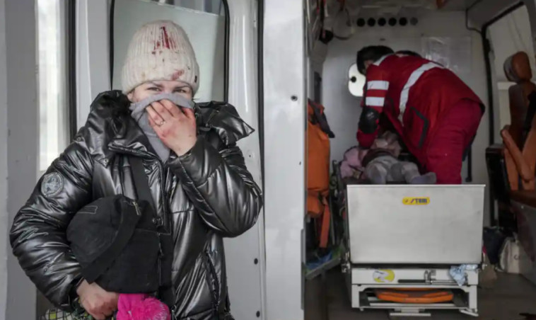 27 בפברואר: אישה במצוקה ממתינה בזמן שהפרמדיקים מבצעים החייאה בילד פצוע. הילד לא שרד (צילום:  Evgeniy Maloletka)
