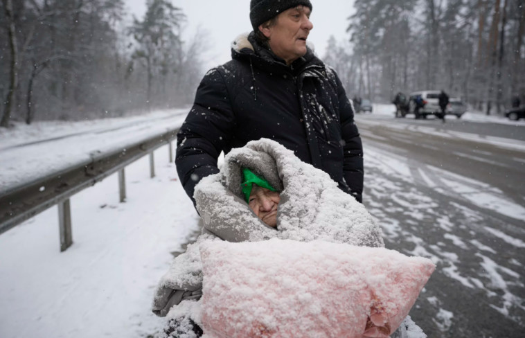 8 במרץ: קשישה על כיסא גלגלים מכוסה בשלג בזמן הפינוי מהעיר אירפין