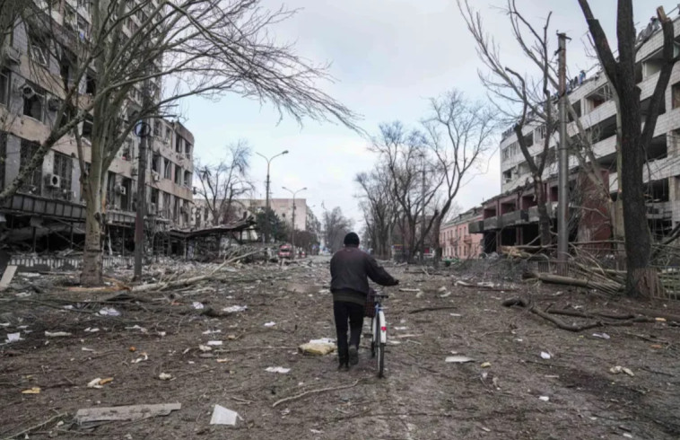 12 במרץ: גבר הולך עם אופניים בין ההריסות של העיר מריופול 