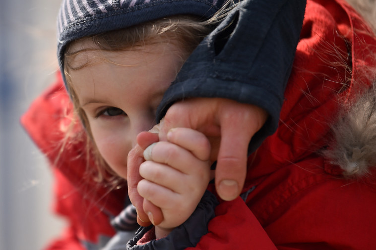 ילדה מחזיקה את ידה של אמה לאחר שנמלטה מאוקראינה לרומניה