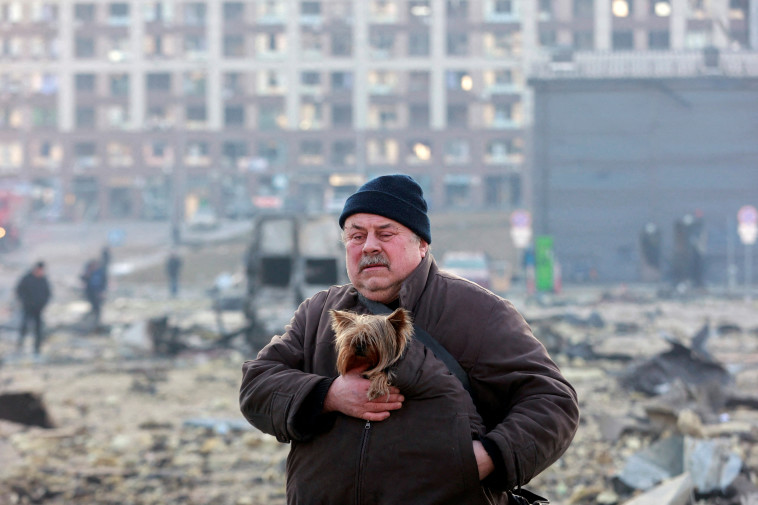 21 במרץ: אוקראיני שומר על חיית המחמד שלו אחרי הפצצת מרכז קניות במחוז פודילסקי, קייב (צילום: REUTERS/Serhii Nuzhnenko)