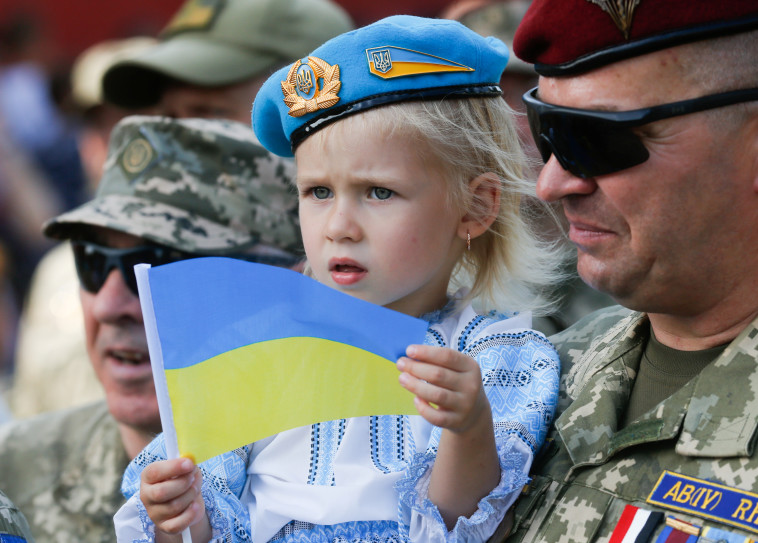 24 במרץ: חייל ובתו נושאים בגאווה את דגל אוקראינה במצעד המגינים של קייב, לציון חודש מיום תחילת המלחמה (צילום: REUTERS/Valentyn Ogirenko)