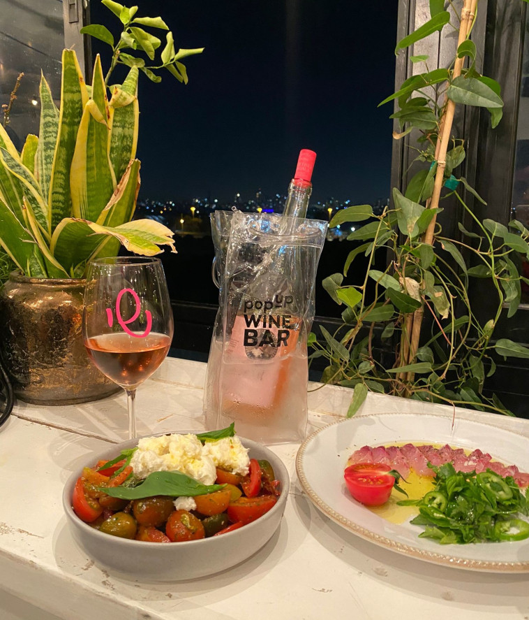 סשימי דג וסלט קפרזה, לצד יין רוזה מצפון ספרד והנוף האורבני של תל אביב