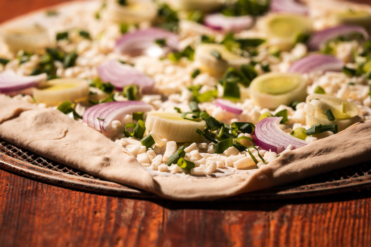 פיצת פרא בצלים: שמנת, מוצרלה, בצל סגול, כרישה, בצל ירוק, חמאת שום ואבן יוגורט מגורדת מעל