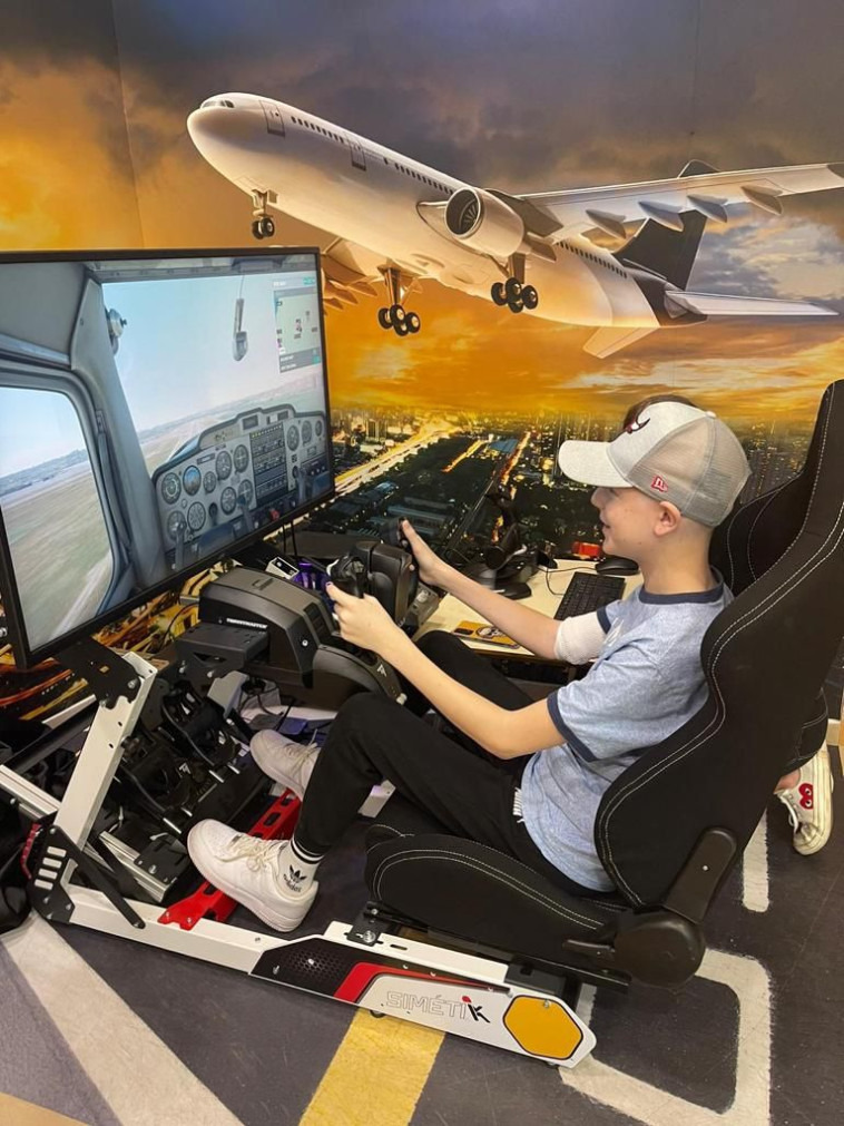 מדריכים ילדים חולי סרטן בבית רחשי לב בשיעורי טיסה על סימולטור טיסה מקצועי