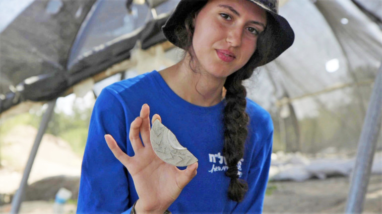 המש''צית אביב ויצמן מחזיקה את שבר 'מראת הכשפים' שגילתה באושה העתיקה (צילום: אמיל אלג'ם, רשות העתיקות)